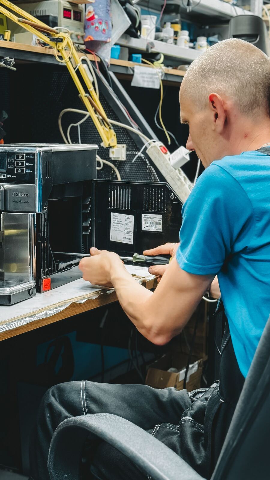 Technician unscrewing the rear housing of a bean-to-cup coffee machine