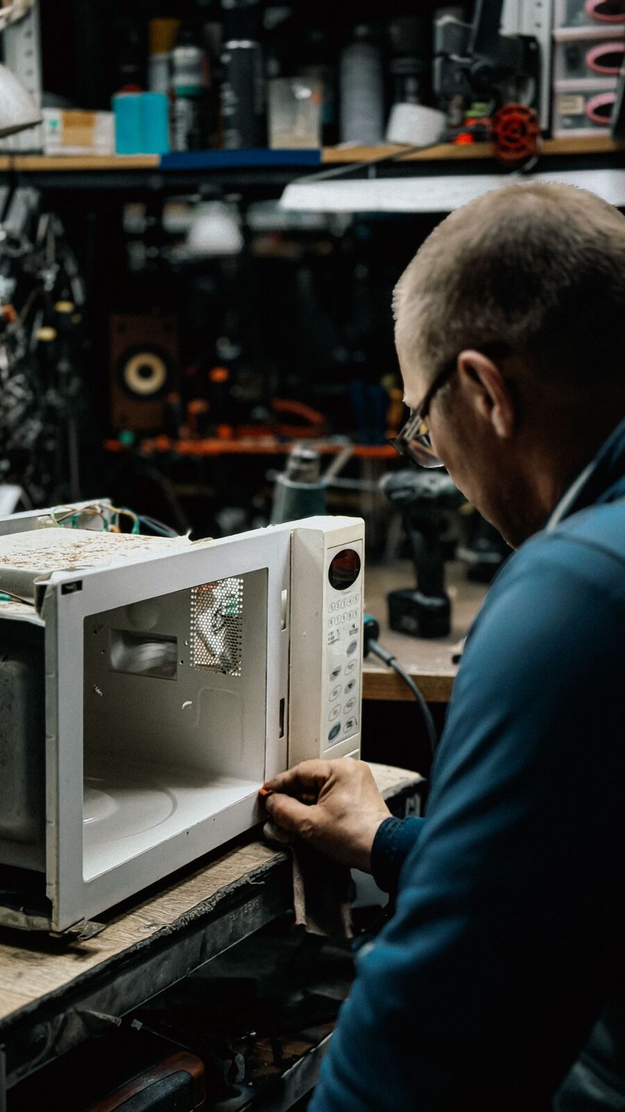 Technician inspecting the inside of a microwave oven with its cover removed