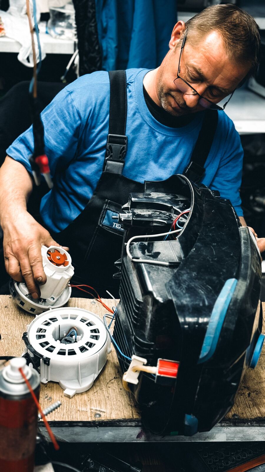 Technician holding a replacement motor next to an opened vacuum cleaner