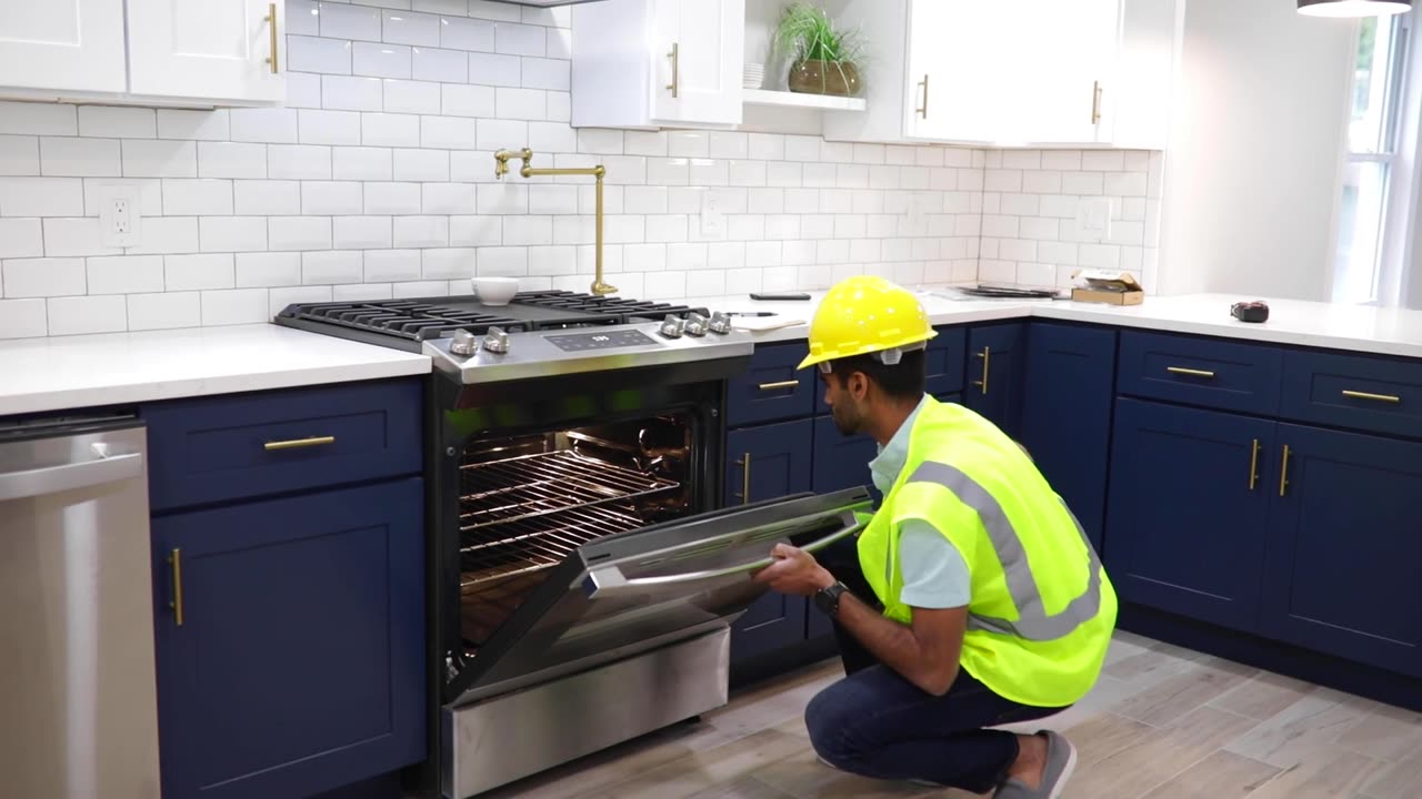 Technician inspecting an open oven door on a stainless steel kitchen range